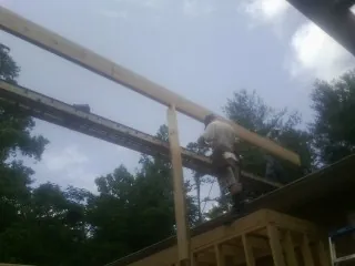Carpenter setting a ridge beam over a new addition frame — Ice Dam Removal by Roofing Brothers in Hillpoint