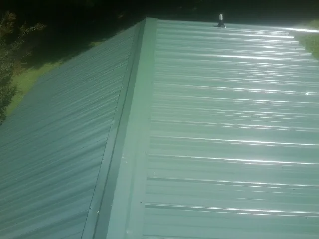 New green metal panels meeting at the ridge of a roof — Flat Roof Repair work by our crew in Hillpoint