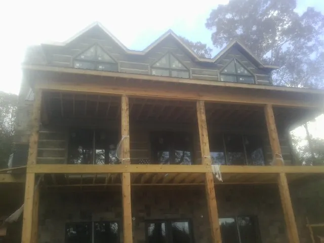 Dormers and porch framing on a large log home under construction — Roof Coating work by our crew in Hillpoint