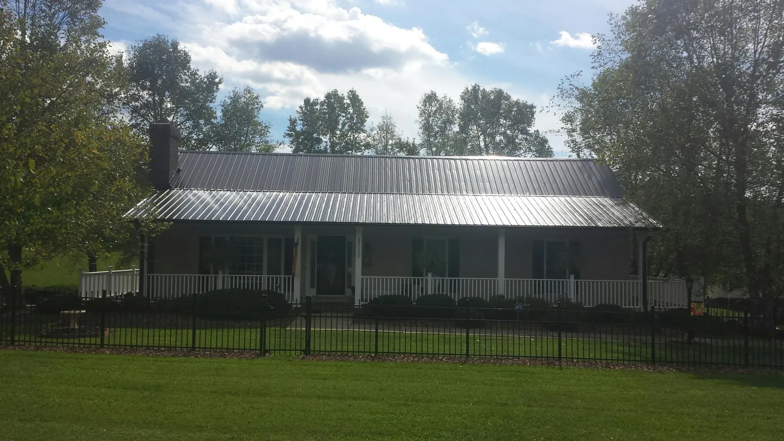 Gray metal roof on a brick ranch with a full width front porch — Gutter Guard Installation work by our crew in Hillpoint