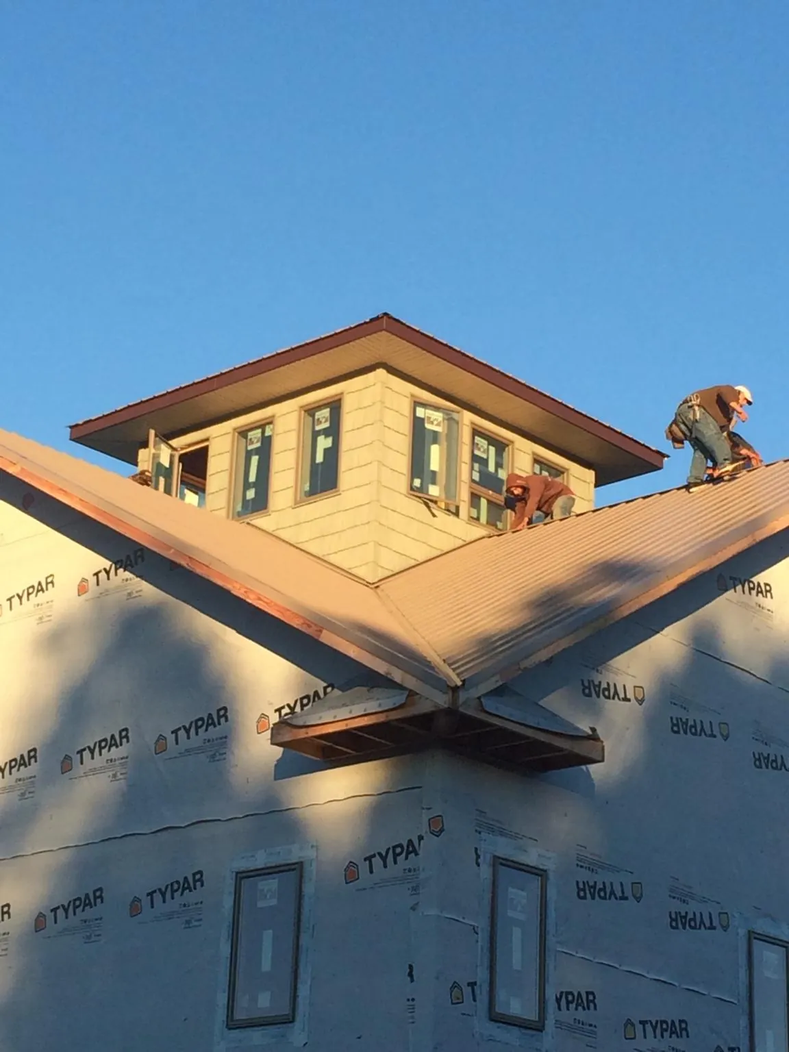 Roofers working around a rooftop cupola on a new metal roof at sunset — Roof Waterproofing in Hillpoint by Roofing Brothers